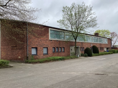 Außenansicht auf die Sporthalle Berentelg Mettingen. Rote Klinker und große Fenster. Im Vordergrund ein Parkplatz