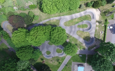 Eine Luftaufnahme vom Pumptrack Mettingen. Es sind die verschiedenen Fahrwege, Hürden und Sprungmöglichkeiten zu sehen.