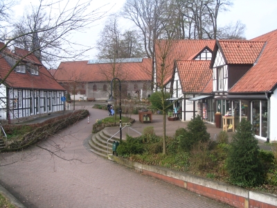 Außenansicht auf den Mettingen Schultenhof. Links und rechts sind Fachwerkhäuser in der Mitte ein gepflasterter Platz mit Büschen und einer Treppe