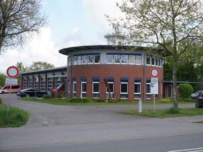 Außenansicht des Feuerwehrhaus Mettingen. ein rundes Klinkergebäude mit Flachdach und vielen Garagen.