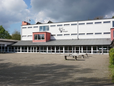 Blick auf den Schulhof mit Tischtennissplatten und im Hintergrund die Josef-Schule Mettingen.