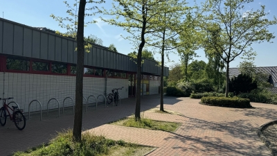 Außenansicht auf das Hallenbad Mettingen. Fahrradständer und ein gepflasterter Gehweg. Im Hintergrund das Hallenbad Mettingen