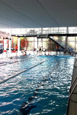 Innenansicht des Hallenbad Mettingen. Schwimmbahnen im Vordergrund und Einstiegtreppen rechts. 